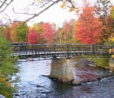 Historic Truesdell truss bridge flanked by autumn colors in Tilton
